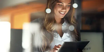 Young female business professional viewing a digital tablet device in a nighttime office