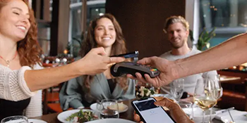 Young people in a restaurant paying for food with phone and EPOS device