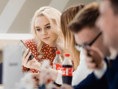 Students seated around table viewing a mobile device in educational setting