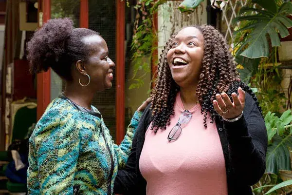 Two women standing outside talking and looking up at the sky