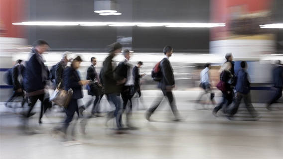 Blurred image of people moving through a modern transport facility space like a train station or airport