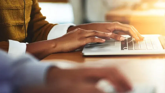 Female business professional seated working on laptop device