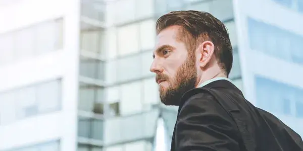 Businessman standing outside office buildings staring into the distance